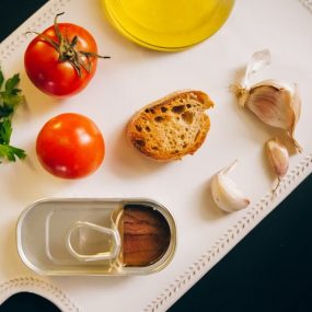 Fresh ingredients for making Catalán toast, including tomatoes, anchovies, and garlic.
